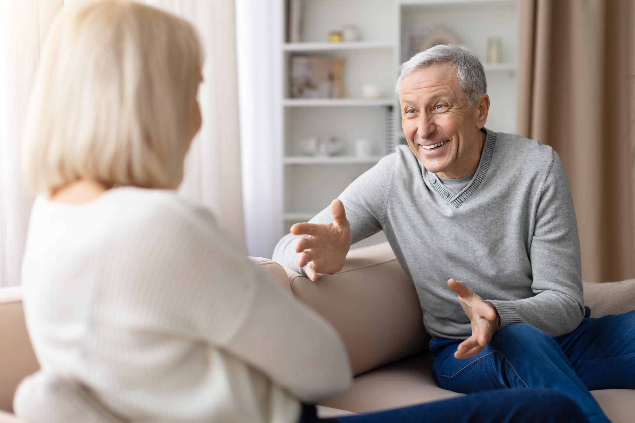 A woman sitting on a couch next to an older man.